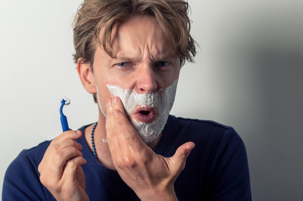 White man using cheap razor nicks himself with the cheap razor